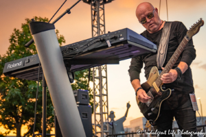 A Flock of Seagulls founder and frontman Mike Score playing the guitar live at Town Center Plaza's Sunset Music Fest in Leawood, KS on June 27, 2019.