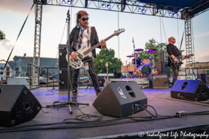 Bass player Pando performing with bandmates Kevin Rankin and Mike Score of A Flock of Seagulls at Sunset Music Fest in Leawood, KS on June 27, 2019.