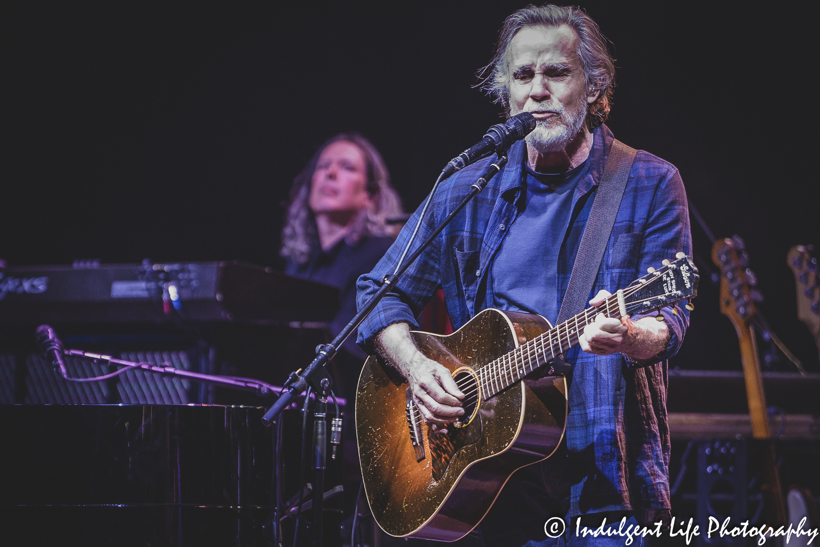 Jackson Browne playing the acoustic guitar with Jason Crosby on keyboards live in concert at Music Hall in downtown Kansas City, MO on June 7, 2022.