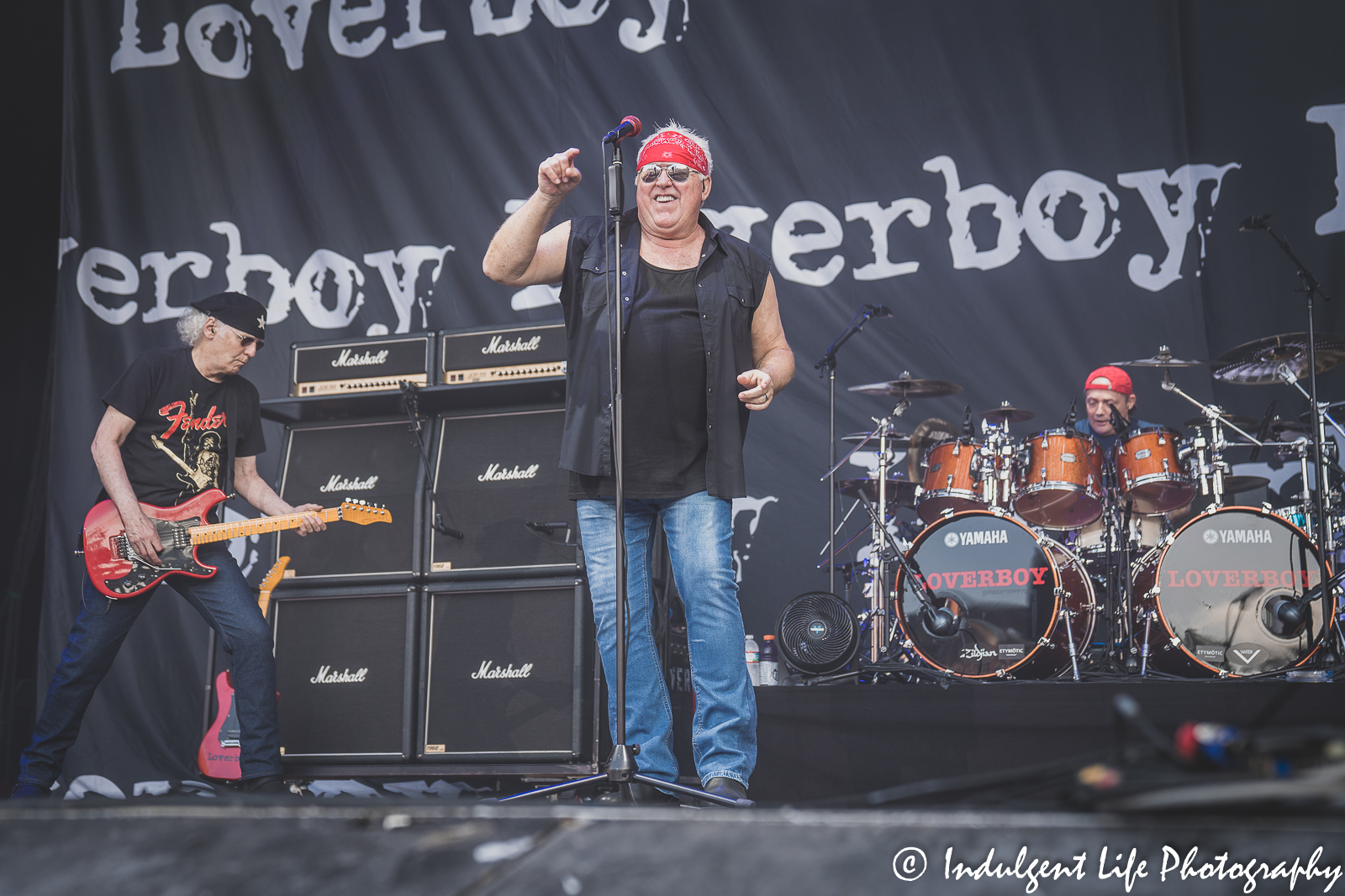 Frontman Mike Reno of Loverboy performing with guitarist Paul Dean and drummer Matt Frenette at Starlight Theatre in Kansas City, MO on June 14, 2022.