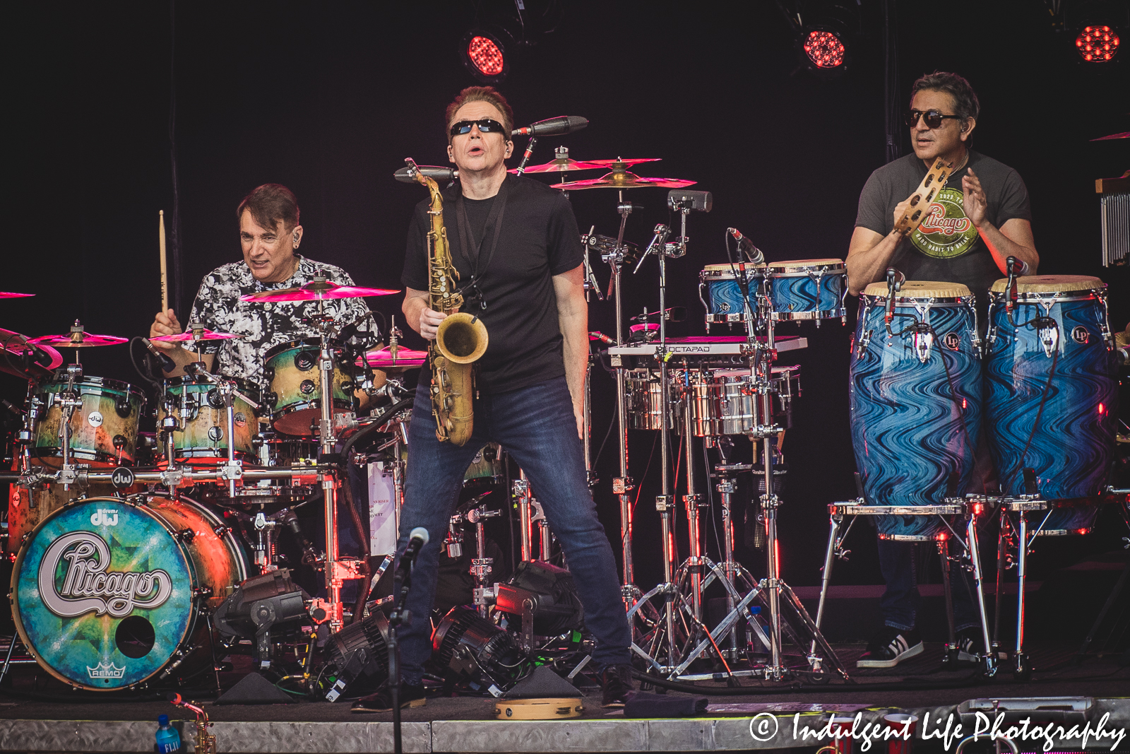 Chicago band touring members Ray Herrmann (saxophone), Walfredo Reyes, Jr. (drums) and Ramon Yslas (percussion) performing together at Starlight Theatre in Kansas City, MO on May 26, 2023.